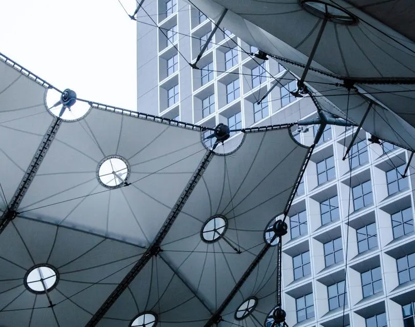 White fabric canopy structure in front of a modern building with square windows